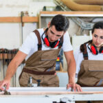 Carpenter and apprentice working together in workshop