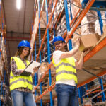 Two young people working together in warehouse storage facility.